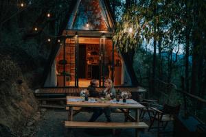a couple sitting at a table in front of a tree house at WANDER CABIN La Marquesa in La Marquesa