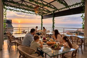 a family eating at a restaurant with the ocean in the background at Hotel Cameo in Kvariati
