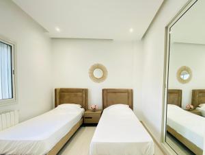 two beds in a room with a mirror at Panoramic 2 bedrooms Ennassr in Ariana