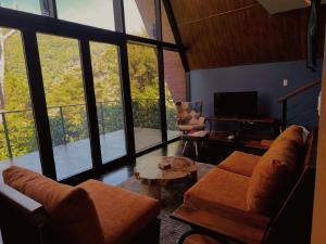 a living room with a couch and a tv and windows at Coffee Cabins - Cabin 4 in Boquete