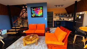 a living room with orange chairs and a kitchen at Coffee Cabins - Cabin 4 in Boquete