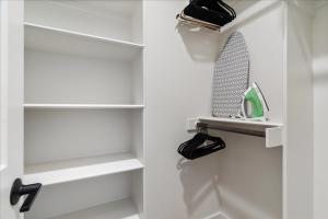 a closet with white shelves and a racket on a shelf at Modern Downtown Apt Fast Wi-Fi & Parking in Austin
