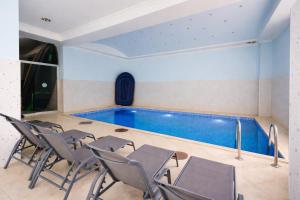 a pool in a room with chairs and a swimming pool at Hotel Cameo in Kvariati