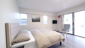 a white bedroom with a bed and a chair at Meet Cottage in Vancouver