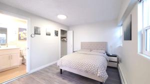 a white bedroom with a bed and a bathroom at Meet Cottage in Vancouver