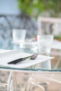 a glass table with a plate and fork and glasses at Rosa di Ischia - Holiday in Ischia Town