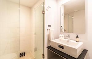 a white bathroom with a sink and a shower at Kukun Reforma & Downtown in Mexico City