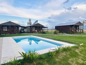 a resort with a swimming pool and two huts at Cabañas Las Escondidas 3 in Chascomús