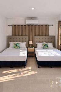 two beds sitting next to each other in a bedroom at Hotel Termaland in Atiquizaya