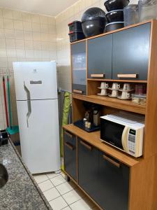 a kitchen with a white refrigerator and a microwave at Family Beach flat - frente ao mar in Barra de São Miguel
