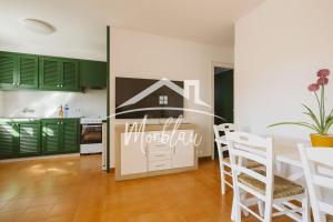 a kitchen with green cabinets and a table and chairs at Sa Torreta 1 in Cala Blanca