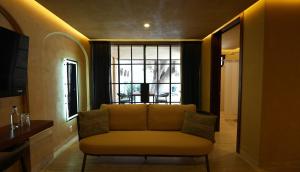 a living room with a yellow couch and a window at 7 Casa Laurel Hotel Boutique in Oaxaca City
