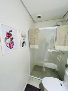 a bathroom with a toilet and some pictures on the wall at Flat Libertad, 404 A, com vaga de garagem in Pelotas +14 photos