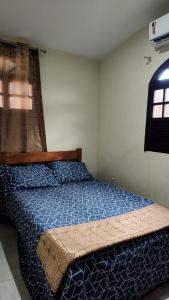 a bedroom with a bed with a blue comforter and a window at Funcional, cômoda e confortável in Camaçari