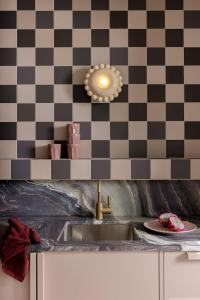 a kitchen with a sink and a checkered wall at Bon Bon Apt 5 - Tonka in Orange