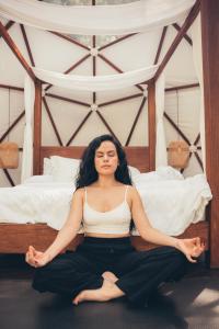 a woman sitting on a bed doing yoga at Domus Glamping Guatapé in Guatapé