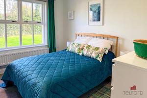 a bedroom with a bed with a blue comforter and two windows at Woodlodge Retreat in Holywood