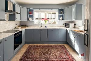 a kitchen with blue cabinets and a rug at Woodlodge Retreat in Holywood