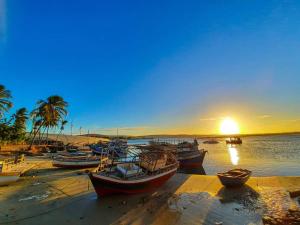 a group of boats parked on a beach with the sunset at Pousada Aconchego em Mundaú in Trairi