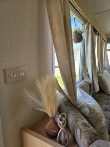 a window with curtains and a vase with a feather at Loulex Deluxe in Jaywick Sands +27 photos