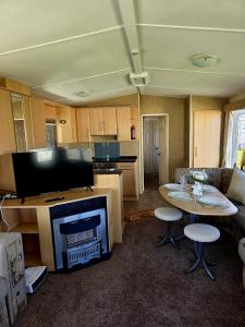 a living room with a tv and a table with chairs at Loulex Deluxe in Jaywick Sands