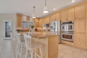 a kitchen with wooden cabinets and a island with bar stools at The Hill Dog Friendly Panoramic Ocean Views in York