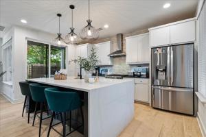 a kitchen with white cabinets and a large island with bar chairs at Spacious 5BR Central Austin Home Sleeps 13 in Austin