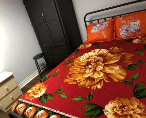 a bed with a red blanket with flowers on it at SHAY-BASEMENT-Holiday Home in Pickering +10 photos