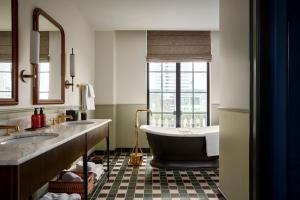 a bathroom with a tub and two sinks and a window at Cincinnati's Fidelity Hotel in Cincinnati