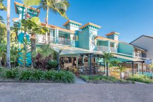 a building with palm trees and a patio at Le Cher Du Monde Adults Only in Port Douglas