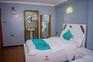 a bedroom with a large white bed and a mirror at Zion Hotel in Nakuru