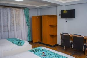 a bedroom with a bed and a desk with chairs at Zion Hotel in Nakuru