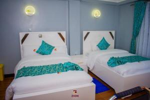 two beds in a room with blue walls at Zion Hotel in Nakuru