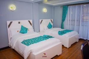 two white beds in a room with blue walls at Zion Hotel in Nakuru