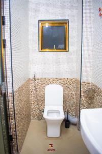 a bathroom with a toilet and a tv on the wall at Zion Hotel in Nakuru