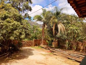 a yard with a fence and palm trees and a mountain at Luz da Serra Hospedagens in Santana do Riacho