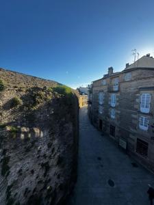 an alley between two buildings next to a stone wall at PASEO CASCO ANTIGUo in Lugo