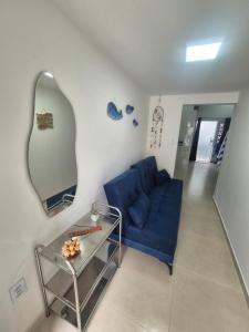 a living room with a blue couch and a mirror at Aconchego do Caju in Arraial do Cabo