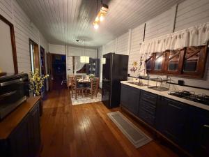 a kitchen with wooden floors and a dining room with a table at Cabana Recanto Dona Ilza in Biguaçu