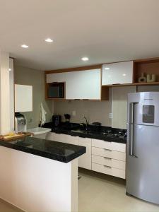 a kitchen with white cabinets and a stainless steel refrigerator at Apto 2 Quartos Novo e Super Confortável in Arapiraca