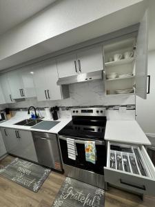 a kitchen with white cabinets and a stove at Private Stylish Suite, Just Bring Your Bags in Edmonton +2 photos