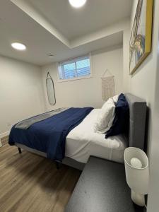 a bedroom with a bed with a blue blanket and a window at Private Stylish Suite, Just Bring Your Bags in Edmonton