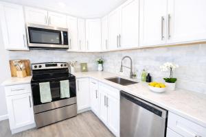 a kitchen with white cabinets and a stove and a sink at Modern Yale Loft Best Location Parking in New Haven