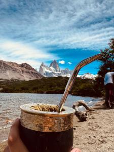 a person holding a drink in front of a mountain at Brumas Patagónicas in El Chalten