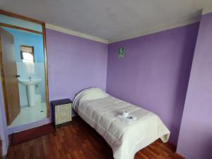 a purple room with a bed and a sink at Inti Ut'ha in Puno
