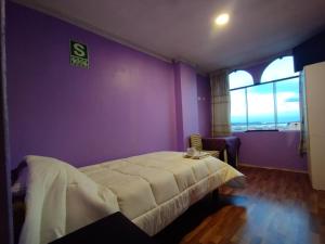 a bedroom with a bed and a purple wall at Inti Ut'ha in Puno