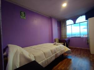 a bedroom with a bed and a purple wall at Inti Ut'ha in Puno