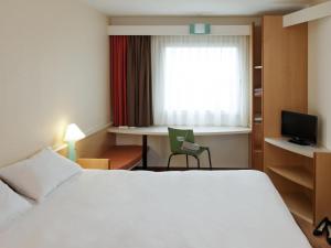 a hotel room with a bed and a desk and a window at ibis Fribourg in Fribourg