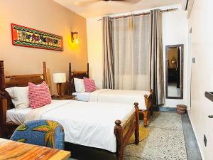 a hotel room with two beds and a table at Nuru House Stone Town Ensuite 3BR Apartment in Zanzibar City