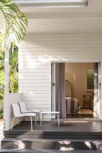 a porch with a chair and a table and a bed at Cove Studios in Byron Bay